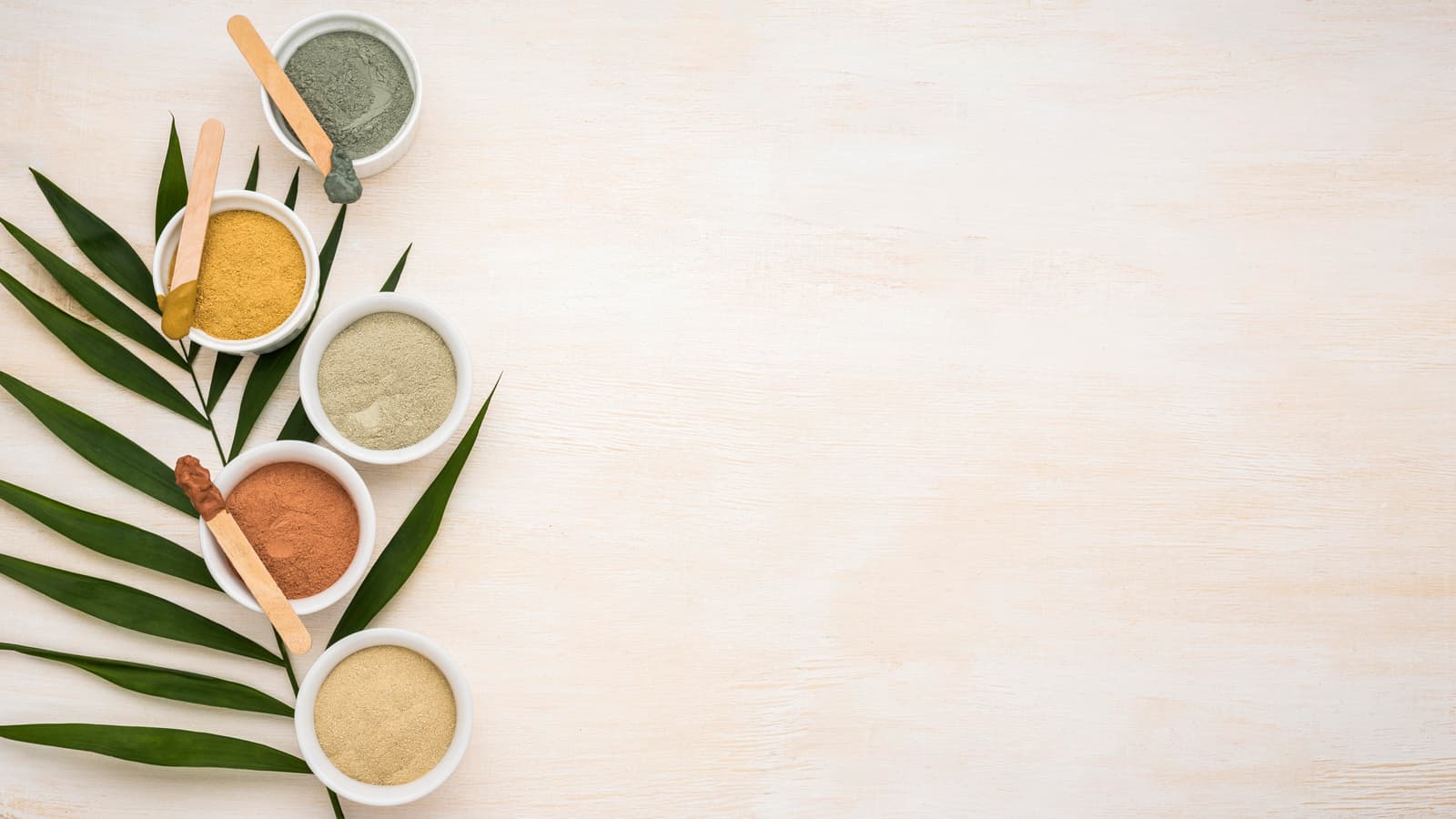 Bowls of herbal powders with a palm leaf