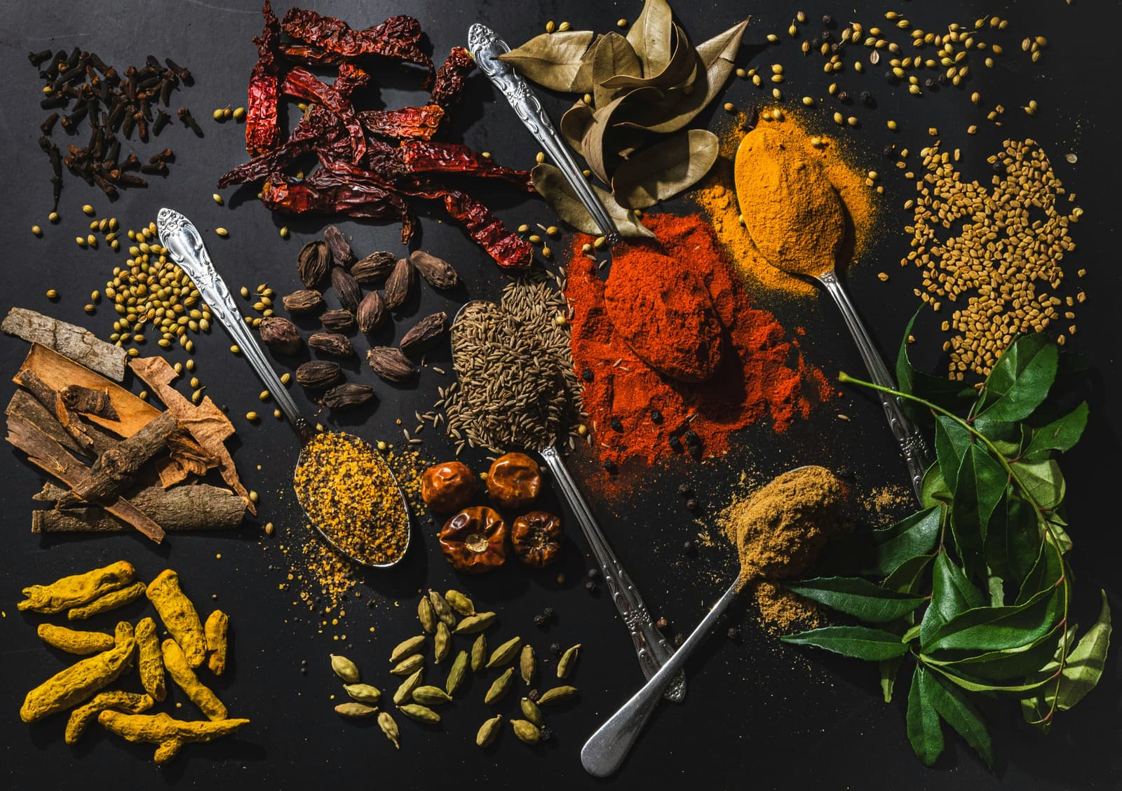 Turmeric, cardamom, cinnamon and other spices on dark slate